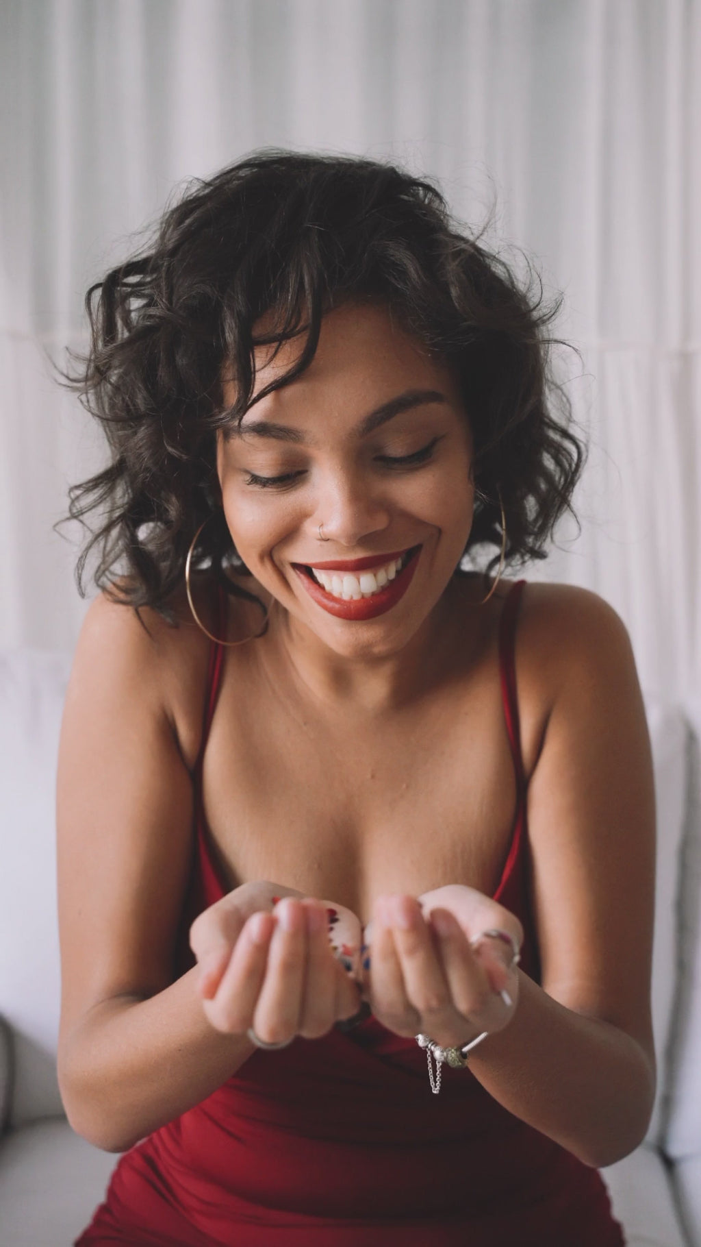 happy black women blowing glitter from hands palmed together in red dress